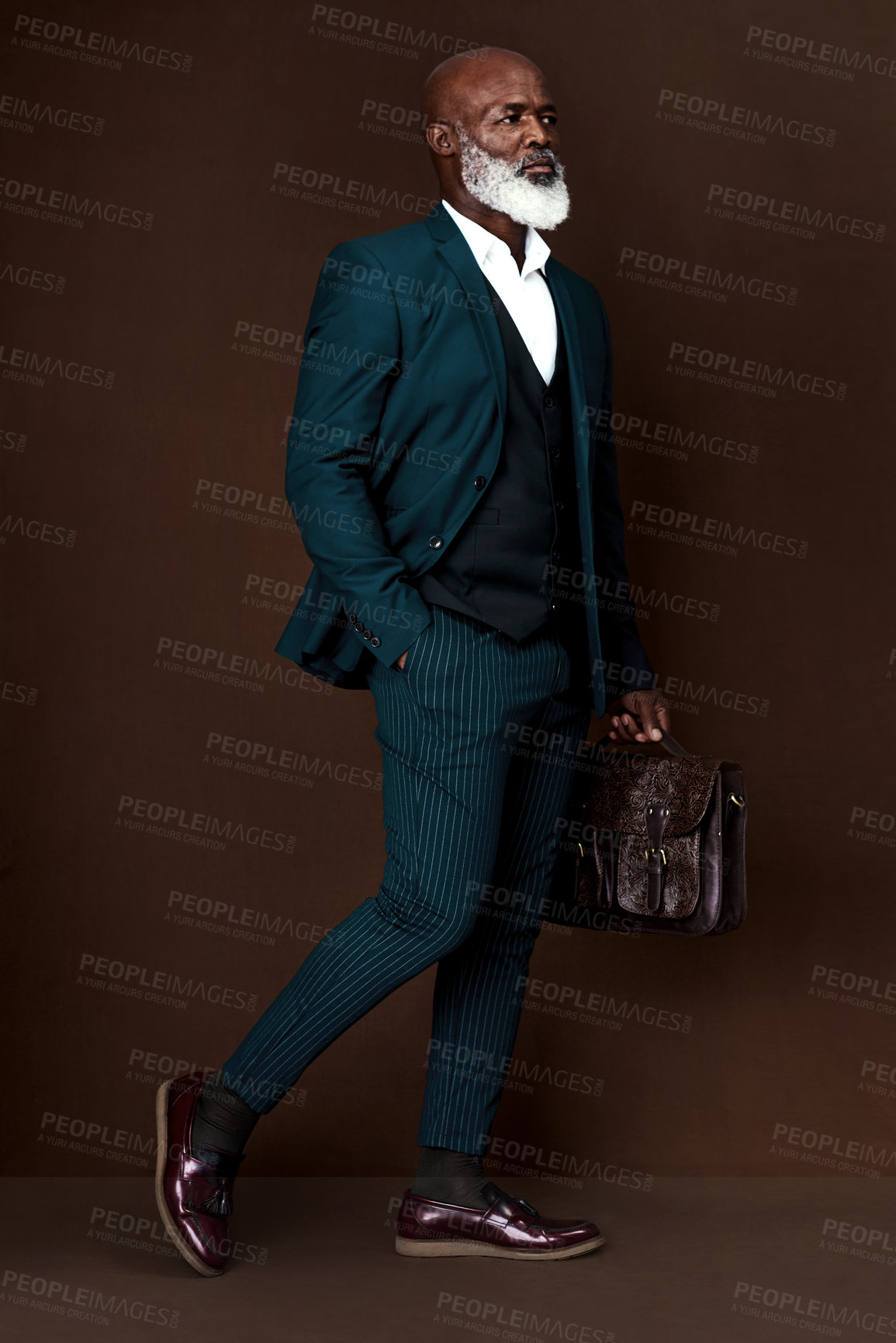 Buy stock photo Studio shot of a well-dressed businessman carrying his briefcase against a brown background