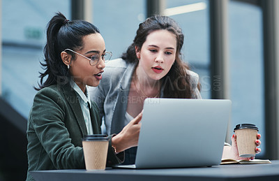 Buy stock photo Shot of two young businesswomen using a laptop during a meeting at a coffee shop