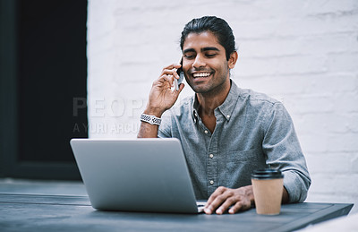 Buy stock photo Shot of a young businessman using a laptop and smartphone in a modern workplace