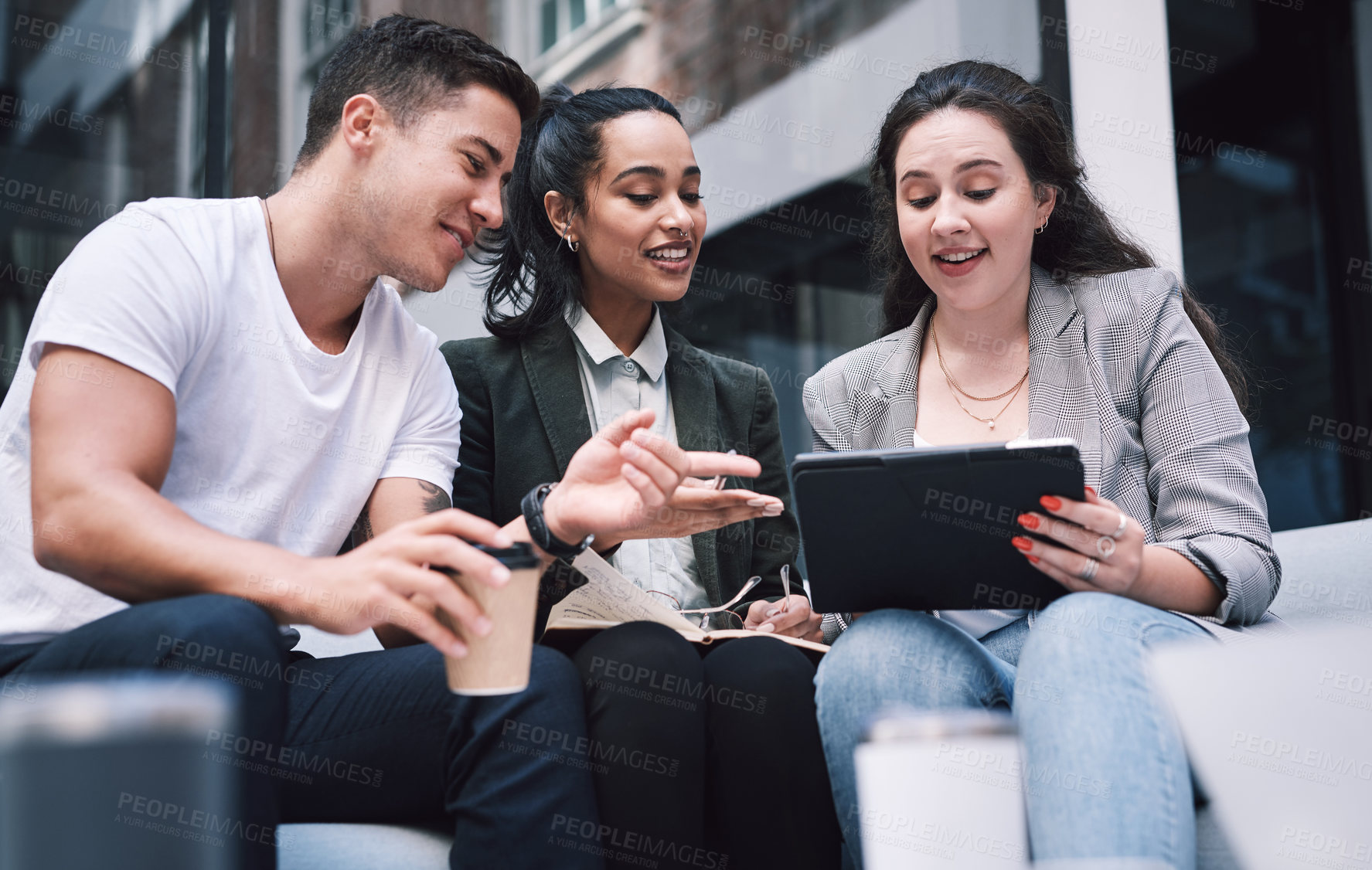 Buy stock photo Shot of a group of young businesspeople using a digital tablet during a meeting at a conference