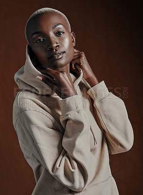 Buy stock photo Studio portrait of an attractive young woman wearing a hoodie and posing against a brown background