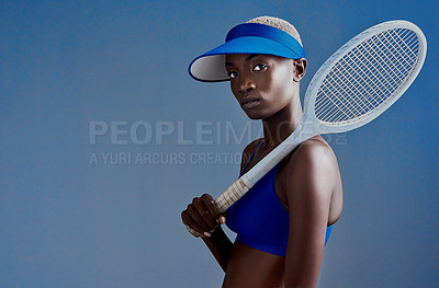 Buy stock photo Studio shot of a sporty young woman posing with a tennis racket against a blue background