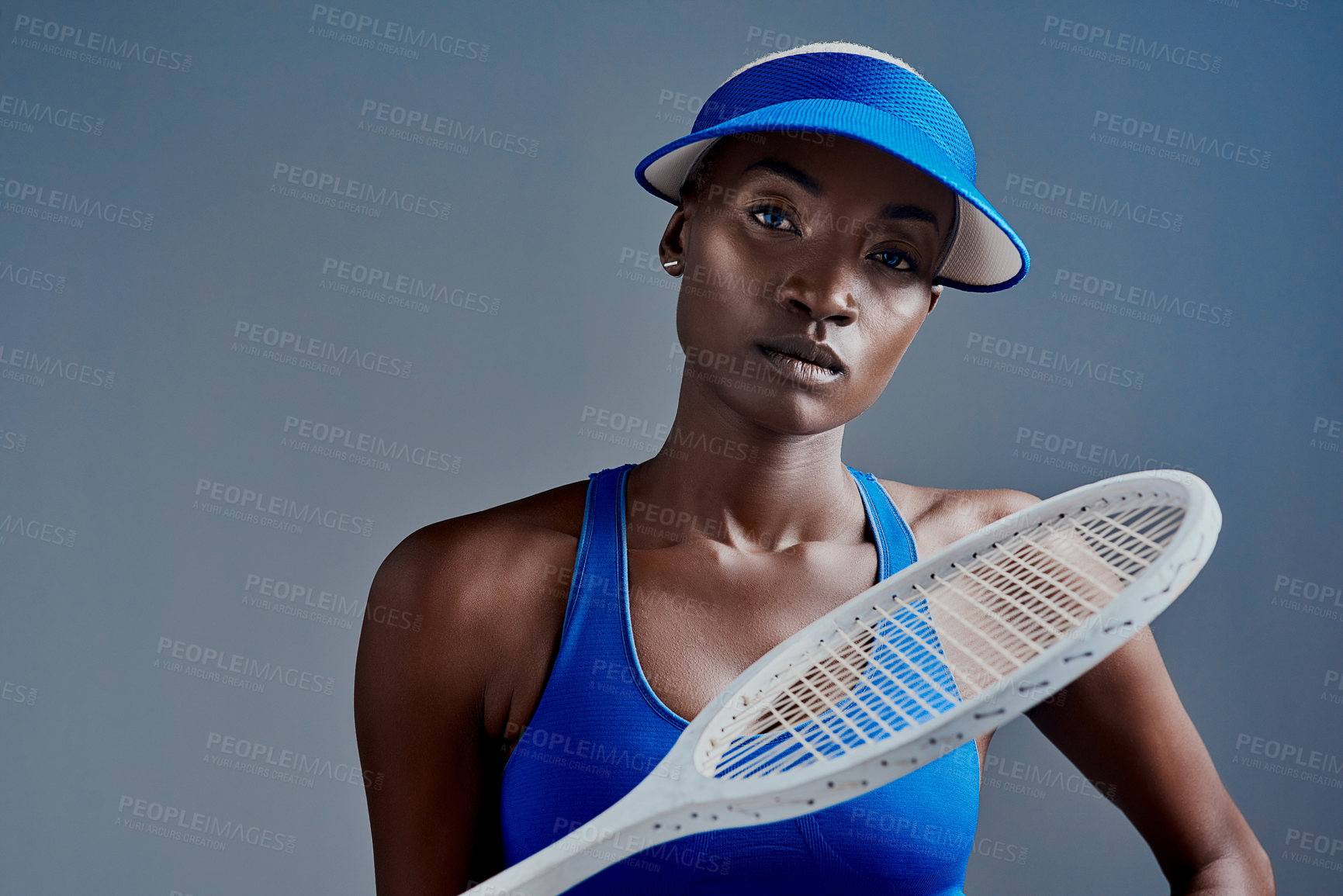 Buy stock photo Black woman, portrait or sports player with tennis racket for fitness or tournament on a blue studio background. Young African, female person or serious athlete with bat for game, match or challenge