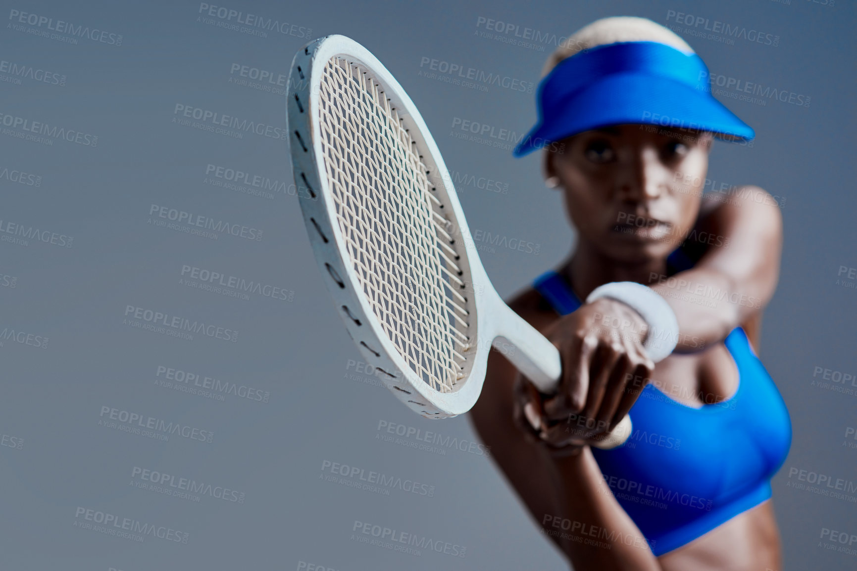 Buy stock photo Studio shot of a sporty young woman posing with a tennis racket against a grey background