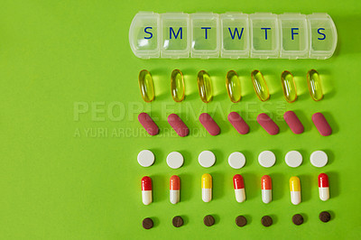 Buy stock photo Studio shot of tablets and a medicine organizer against a green background