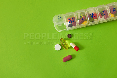 Buy stock photo Studio shot of tablets in a medicine organizer against a green background