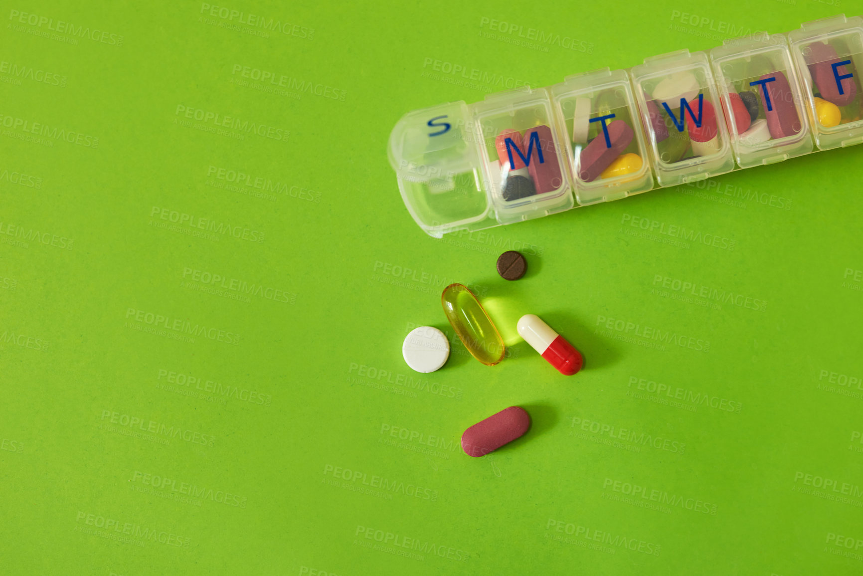 Buy stock photo Studio shot of tablets in a medicine organizer against a green background