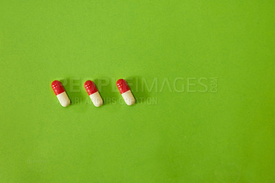 Buy stock photo Studio shot of three capsules against a green background