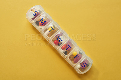 Buy stock photo Studio shot of tablets in a medicine organizer against a yellow background