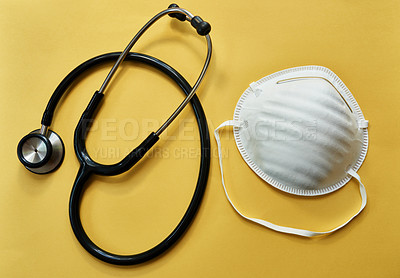 Buy stock photo Studio shot of a stethoscope and mask against a yellow background