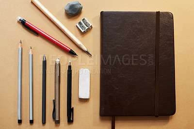 Buy stock photo Studio shot of a sketchpad and other various artistic against a brown background