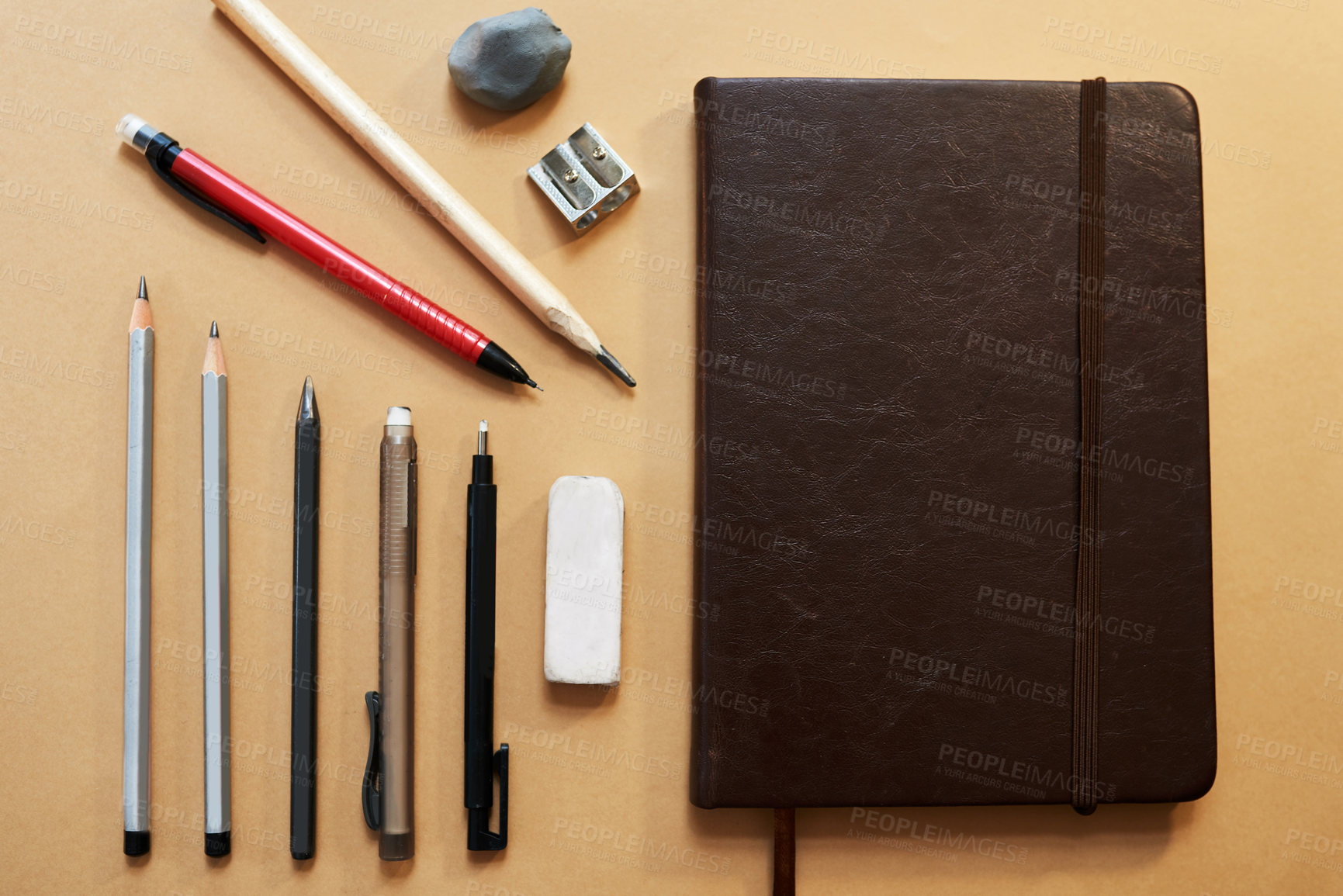 Buy stock photo Studio shot of a sketchpad and other various artistic against a brown background