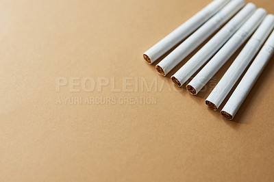 Buy stock photo Studio shot of a row of cigarettes against a brown background