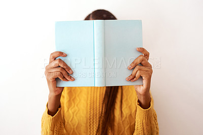 Buy stock photo Studio shot of an unrecognizable woman posing with a book over her face