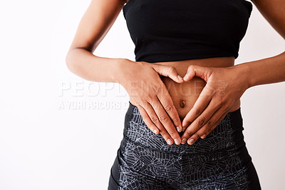 Buy stock photo Studio shot of an unrecognizable woman forming a heart over her stomach