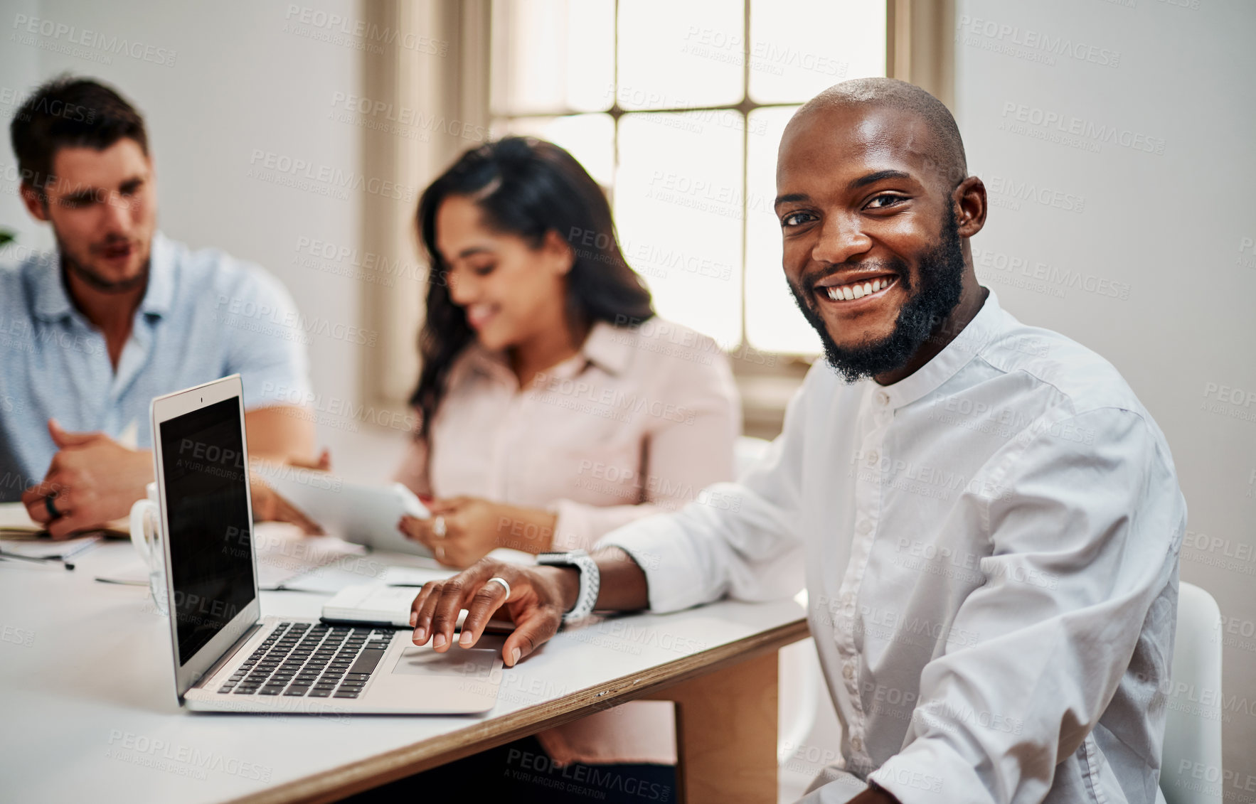 Buy stock photo Portrait of a young businessman having a meeting with colleagues in a modern office