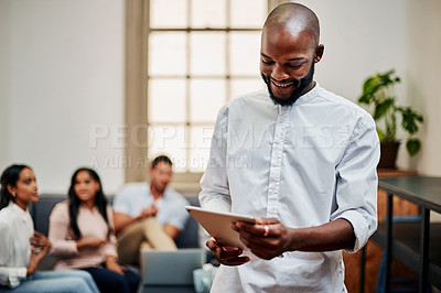 Buy stock photo Shot of a young businessman using a digital tablet with his colleagues in the background