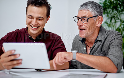 Buy stock photo Shot of two businessmen working together on a digital tablet in an office