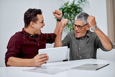 Buy stock photo Shot of two businessmen cheering while working on a digital tablet together in an office