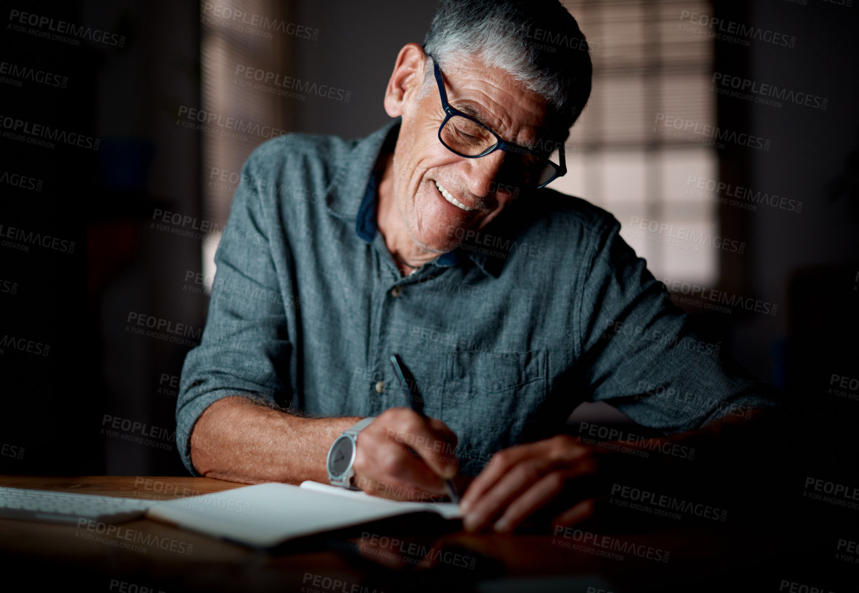 Buy stock photo Shot of a senior businessman writing notes while working in an office at night