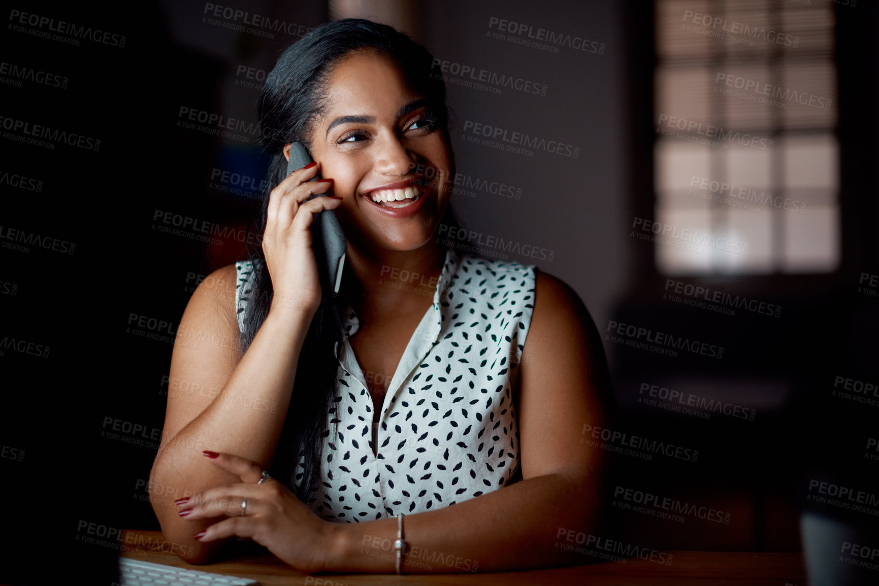 Buy stock photo Shot of a young businesswoman talking on a cellphone in an office at night
