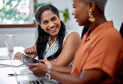 Buy stock photo Shot of two businesswomen working together on a digital tablet in an office