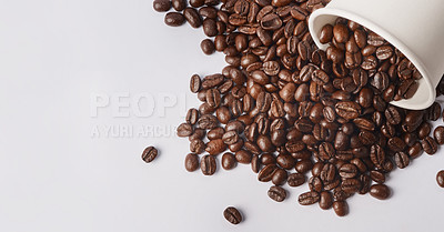 Buy stock photo Studio shot of a tipped over paper cup filled with coffee beans against a white background