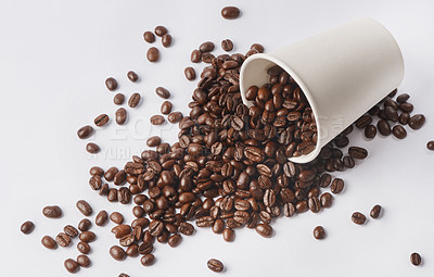 Buy stock photo Studio shot of a tipped over paper cup filled with coffee beans against a white background