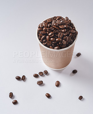 Buy stock photo Studio shot of a paper cup filled with coffee beans against a grey background