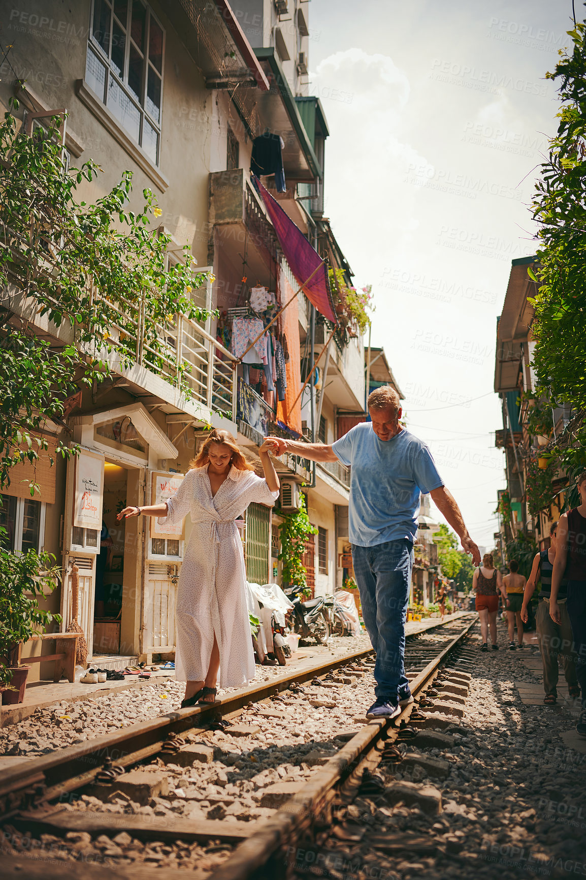 Buy stock photo Shot of a happy couple sharing a romantic moment on the train tracks in the streets of Vietnam