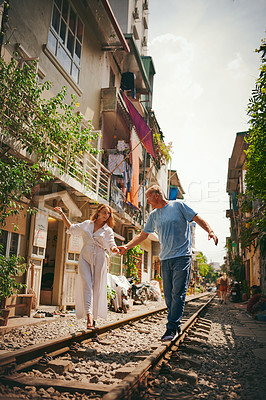 Buy stock photo Shot of a happy couple sharing a romantic moment on the train tracks in the streets of Vietnam