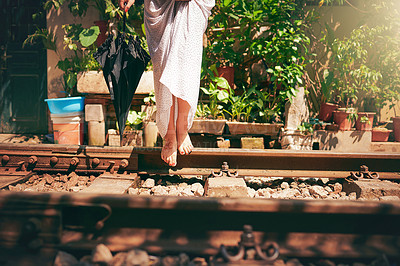 Buy stock photo Cropped shot of a woman walking barefoot on train tracks through the streets of Vietnam