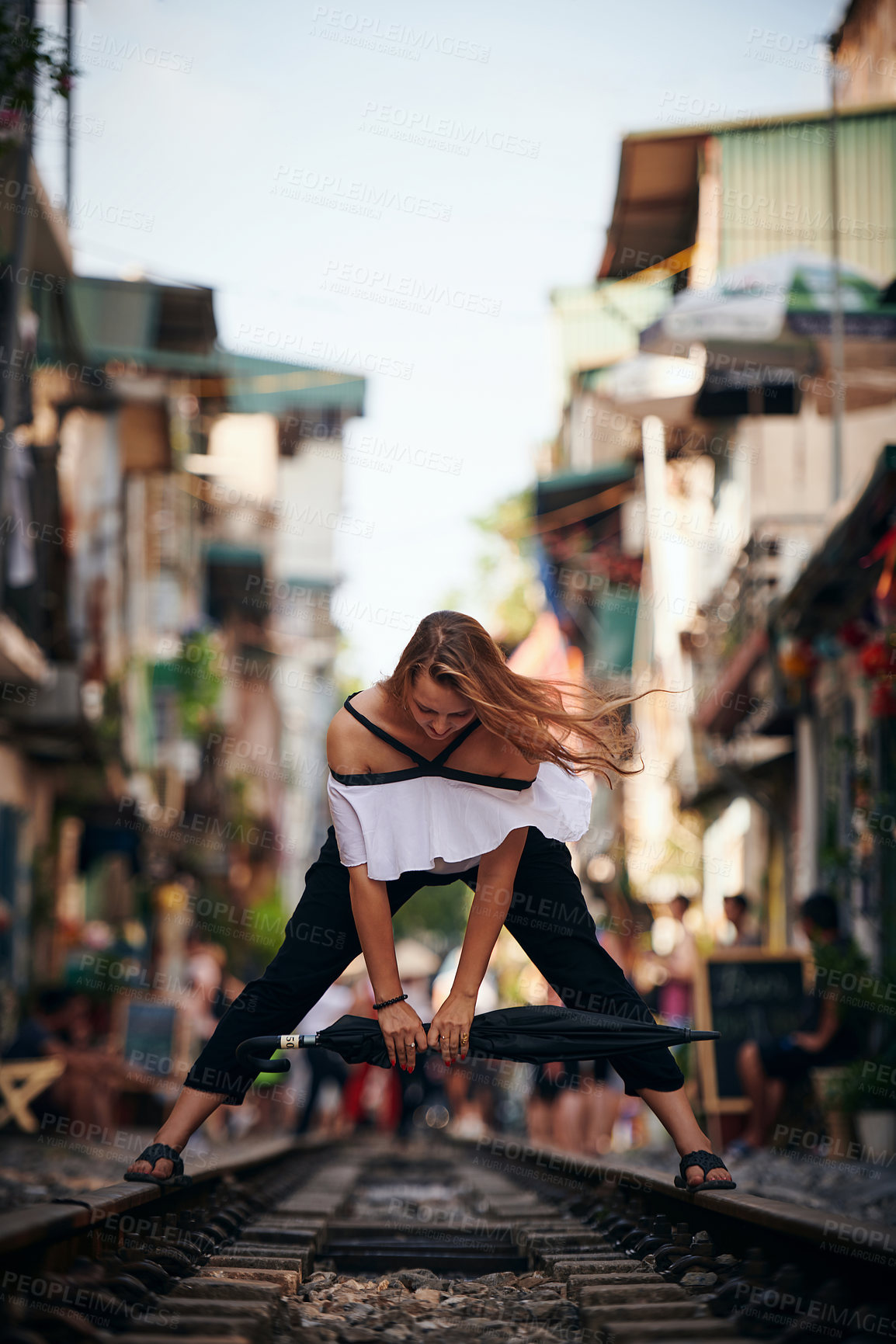 Buy stock photo Woman, umbrella and railway in city for vacation, explore and sightseeing with freedom. Female person, travel and dancing on train track for holiday destination, outdoor adventure and play in Vietnam