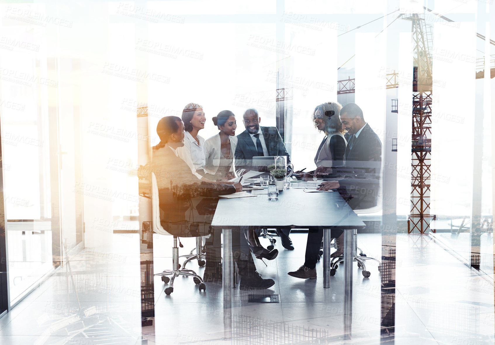 Buy stock photo Shot of a team of businesspeople in a meeting superimposed over a build site
