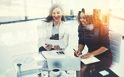 Buy stock photo Shot of two businesswomen using a tablet superimposed over a cityscape