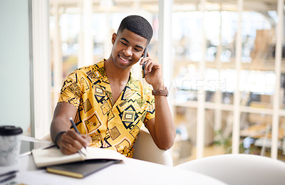 Buy stock photo Shot of a young businessman writing notes while talking on a cellphone in an office
