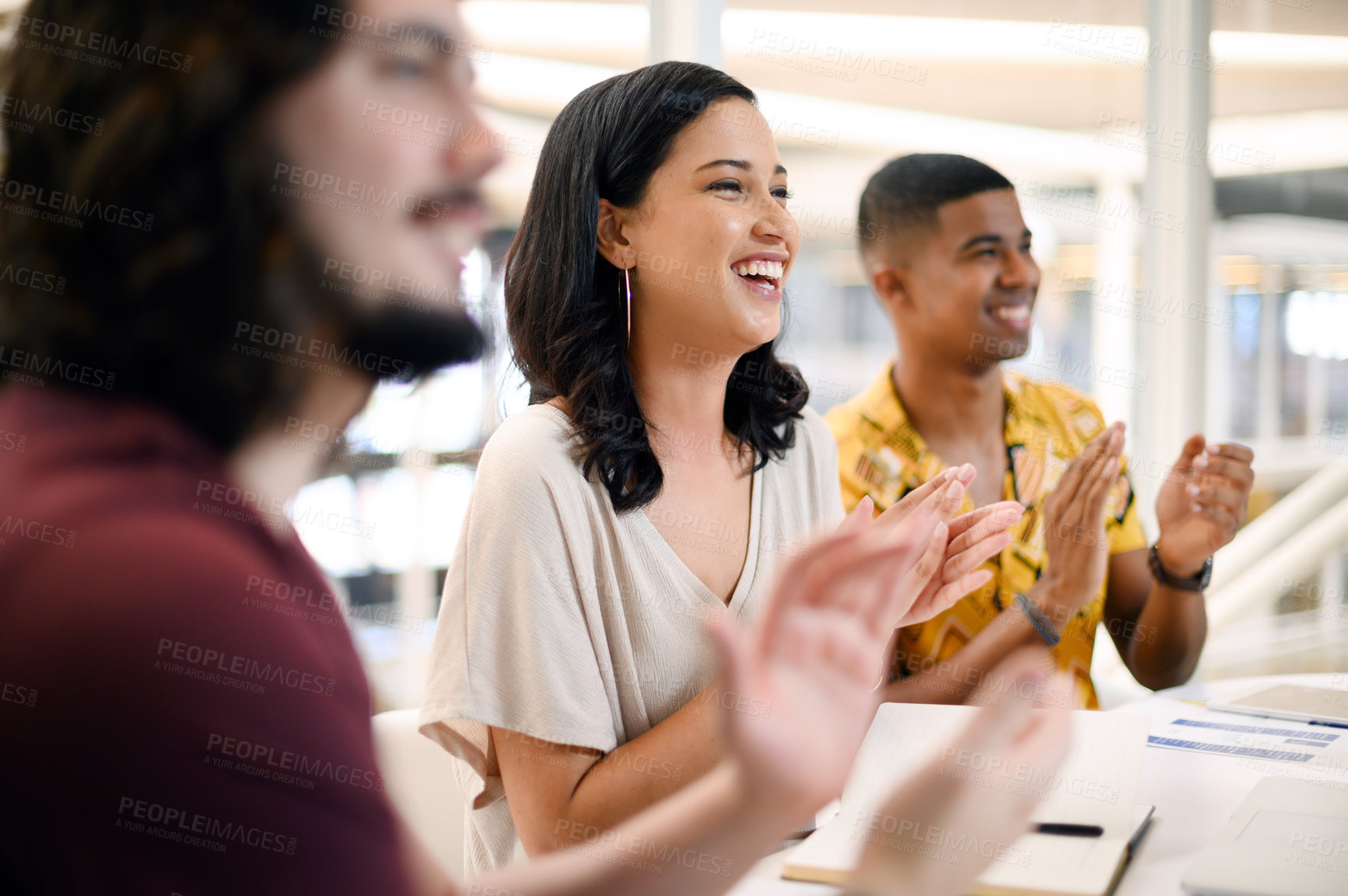 Buy stock photo Shot of a young businesswoman applauding while sitting alongside her colleagues during a presentation in an office