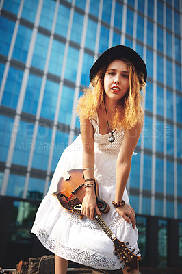 Buy stock photo Shot of a beautiful young woman out in the city with her guitar