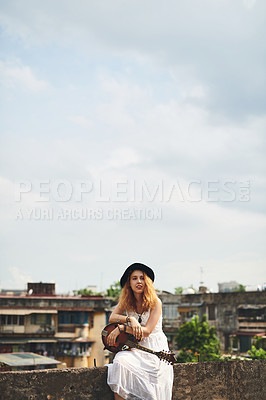 Buy stock photo Shot of a young woman out on a rooftop with her guitar