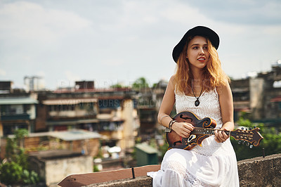 Buy stock photo Shot of a young woman out on a rooftop with her guitar