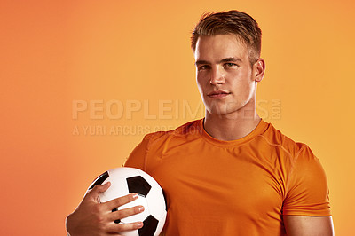 Buy stock photo Studio portrait of a handsome young male soccer player posing against n orange background