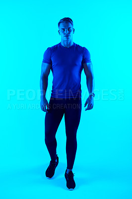 Buy stock photo Studio portrait of a handsome young male athlete posing against a blue background
