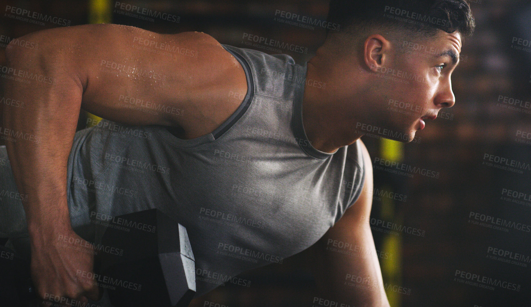 Buy stock photo Shot of a sporty young man exercising with a dumbbell at the gym