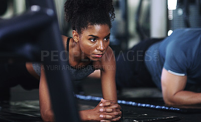 Buy stock photo Shot of a sporty young woman doing plank exercises at the gym