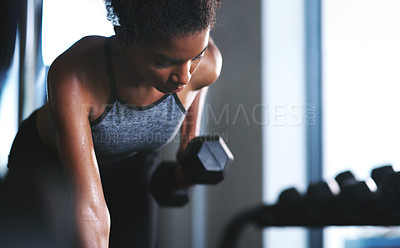 Buy stock photo Shot of a sporty young woman exercising with a dumbbell at the gym