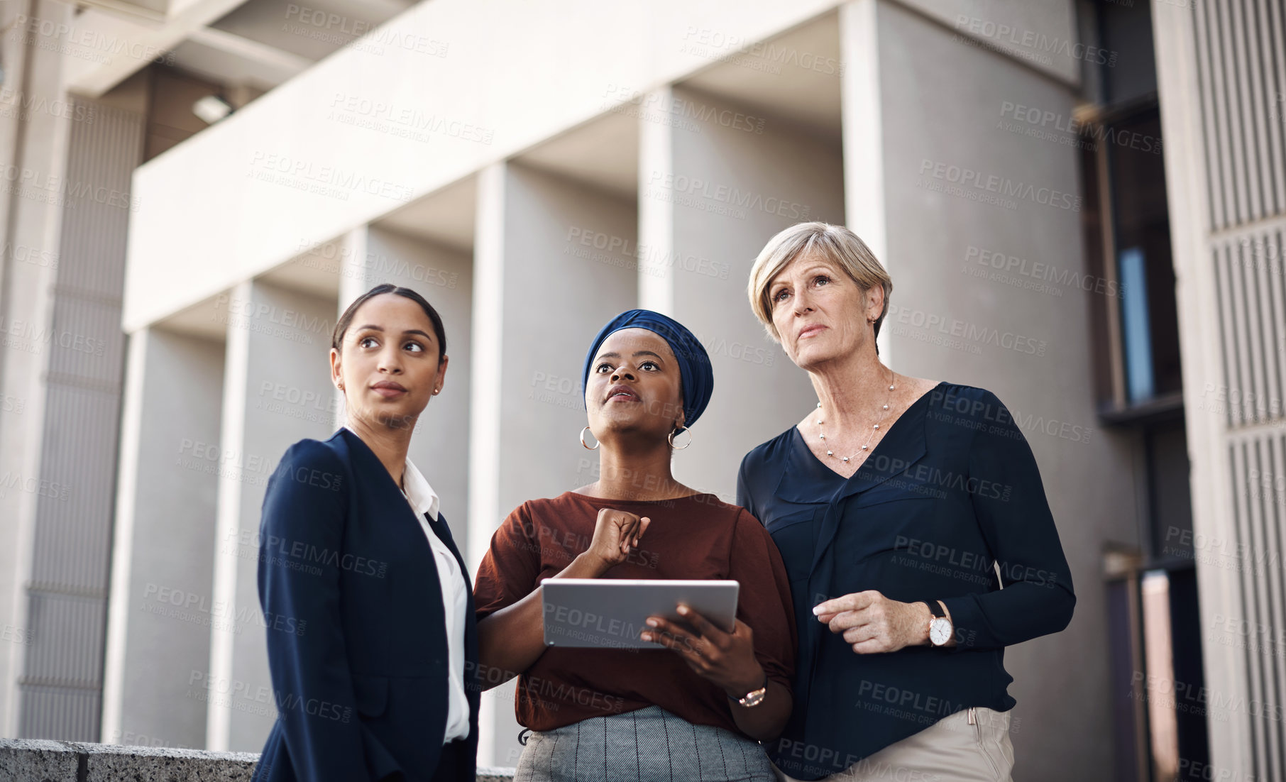 Buy stock photo Shot of a group of businesswomen using a digital tablet together against a city background