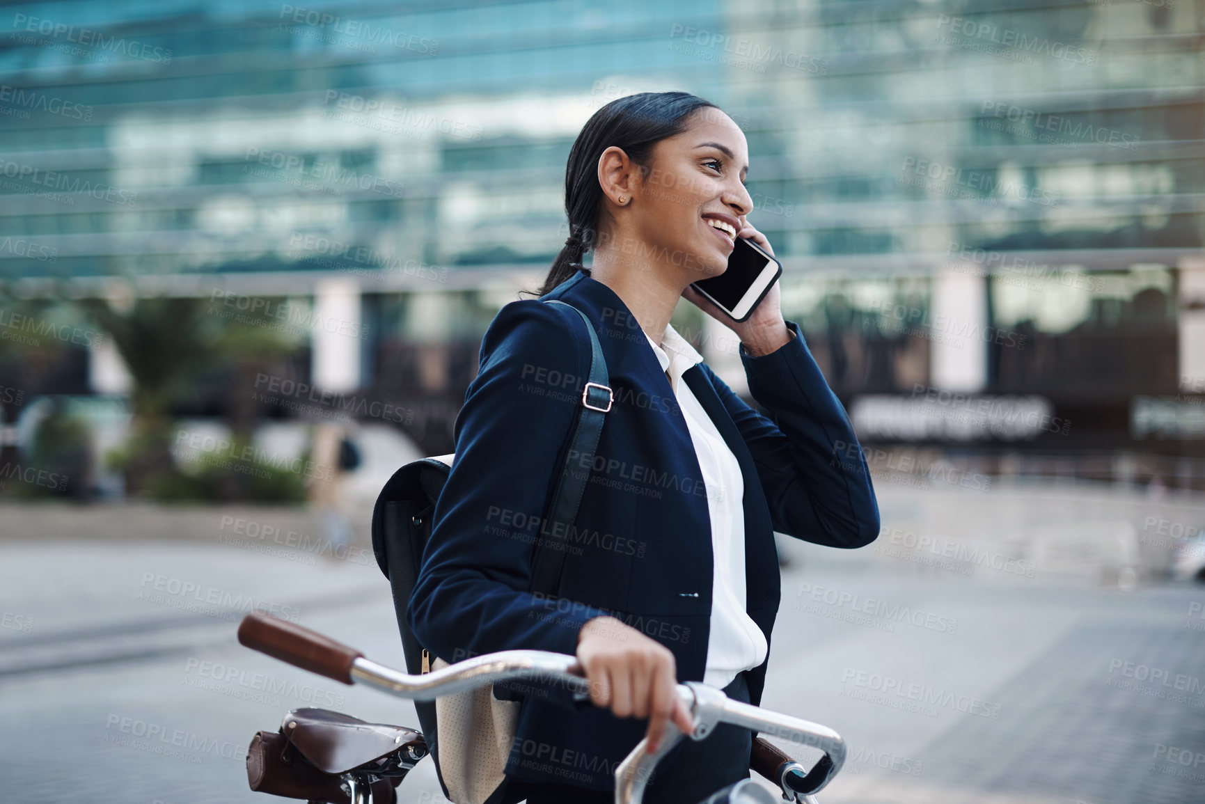 Buy stock photo Shot of a young businesswoman using a smartphone while traveling with a bicycle through the city