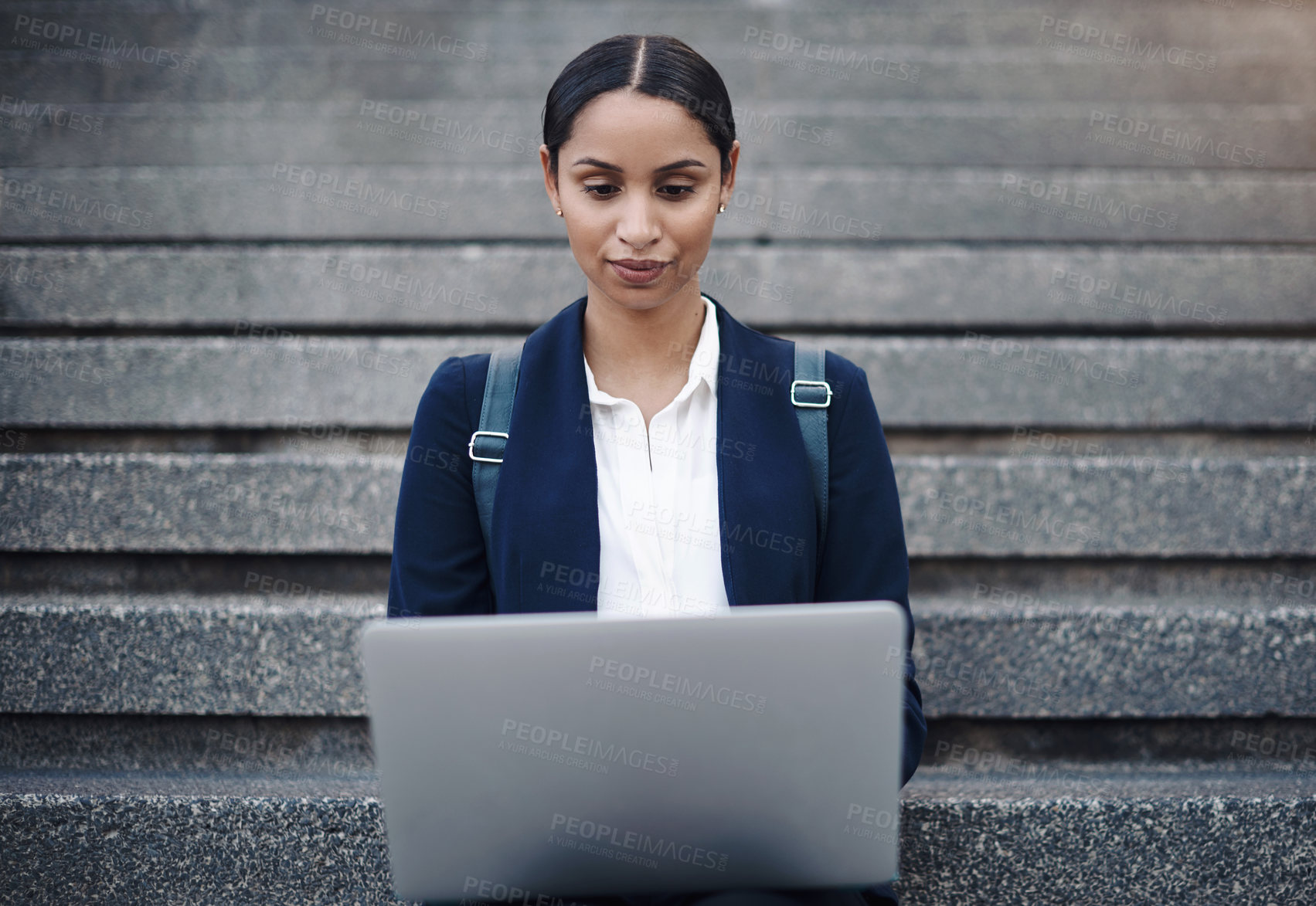 Buy stock photo Shot of a young businesswoman using a laptop on the stairs against a city background