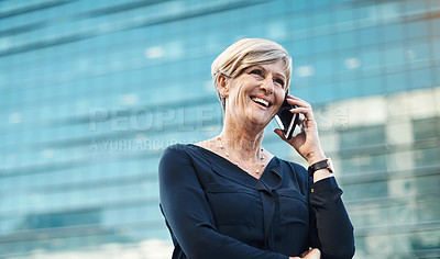 Buy stock photo Shot of a mature businesswoman using a smartphone against a city background