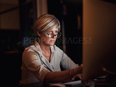 Buy stock photo Cropped shot of an attractive mature businesswoman working on her computer late at night in the office